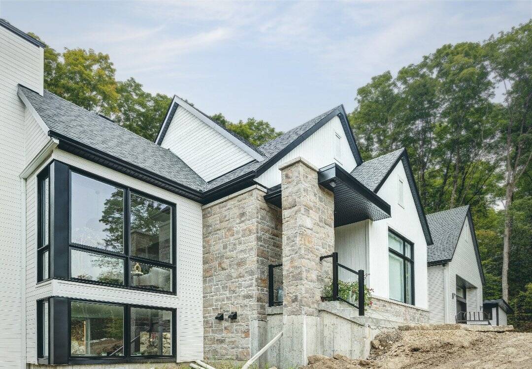 Maison moderne en forêt avec grandes fenêtres et architecture contemporaine.